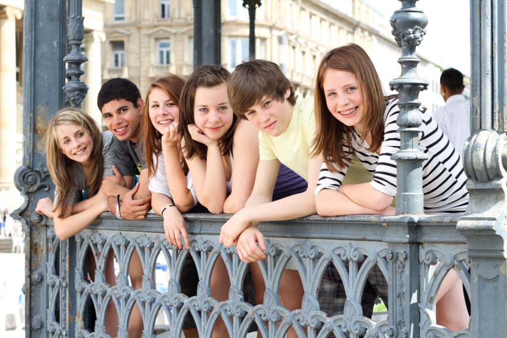 Eine Gruppe von Schülern im Teenageralter lehnt am eisernen Geländer einer Brücke.