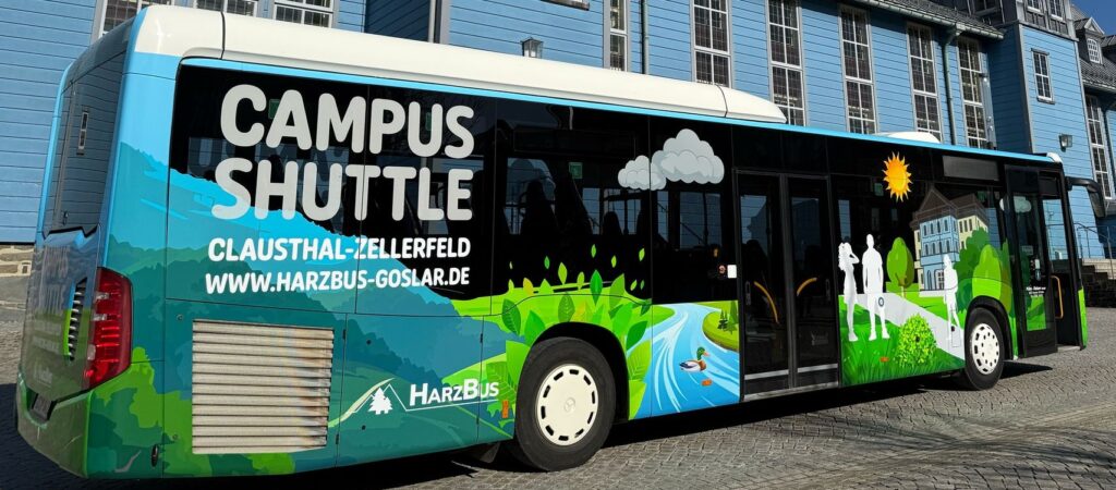 Ein Linienbus der Firma Pülmreisen vor einem hellblauen Gebäude im Harz.