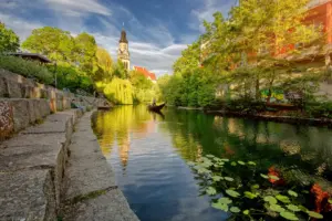 Blick vom Wasser auf einen Kanal mit Gondel in Leipzig.