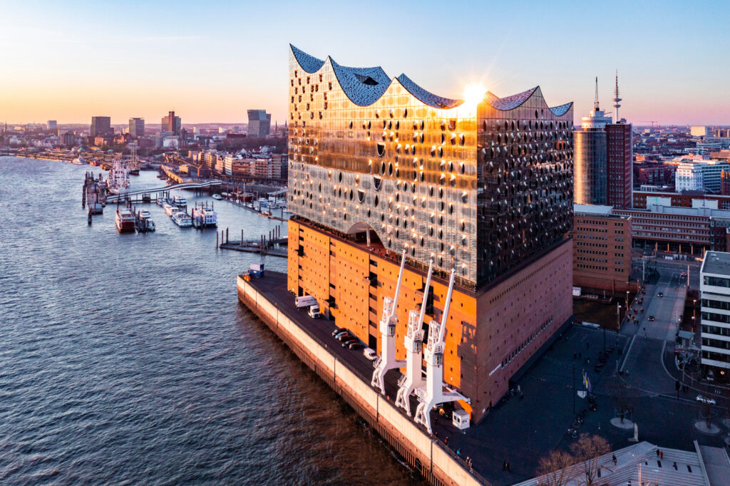 Luftaufnahme der Elbphilharmonie in Hamburg mit Hafen im Hintergrund.