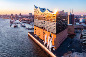 Luftaufnahme der Elbphilharmonie in Hamburg mit Hafen im Hintergrund.