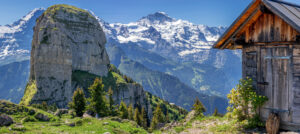 Blick auf die Berge Monch, Eiger und Jungfrau in der Schweiz. Im Vordergrund die Schynige Platte mit Berghütte.