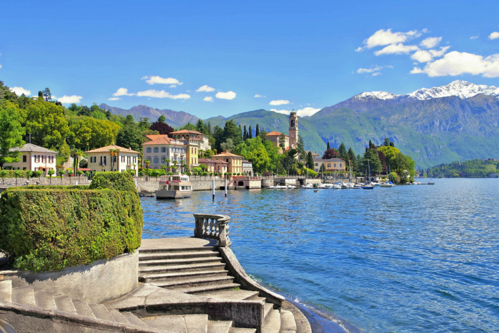 Die Stadt Tremezzo am Comer See in Italien mit einer Steintreppe zum See im Vordergrund.