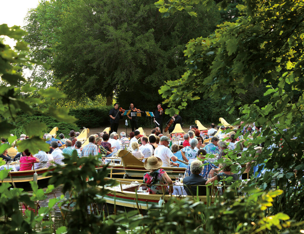Seekonzert mit Publikum in Booten und Geigenspielern auf der Bühne in Wörlitz.