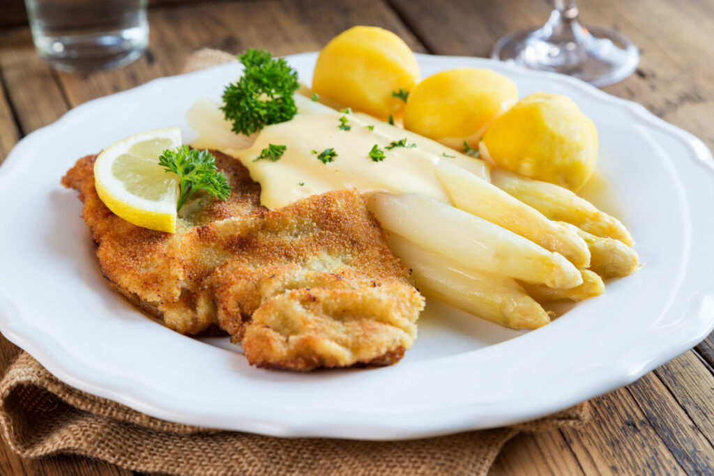Ein Teller mit Spargel mit Schnitzel und Salzkartoffeln.
