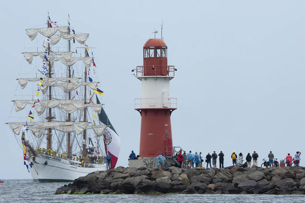 Ein Großsegler fährt vor dem Leuchtturm während der Hanse Sail in Rostock.