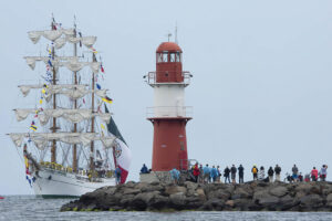 Ein Großsegler fährt vor dem Leuchtturm während der Hanse Sail in Rostock.