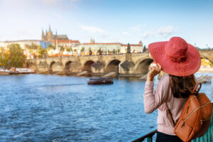 Die Karlsbrücke in Prag. Eine junge Frau mit Hut im Vordergrund.