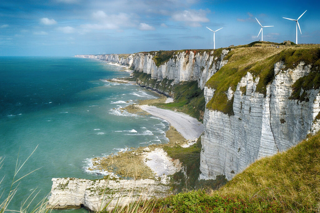 Blick auf die Alabaster Kliffs an der Normandieküste in Frankreich mit Windrädern im Hintergrund.