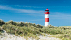 Ein rot-weißer Leuchtturm in den Dünen auf der Insel Sylt.