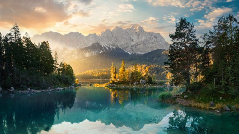 Blick auf die Zugspitze im Sonnenschein mit einem See im Vordergrund.